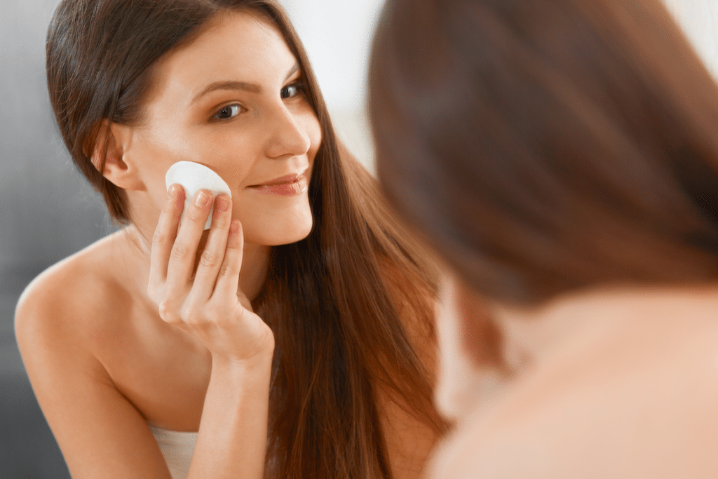 Woman cleaning her face with astringent