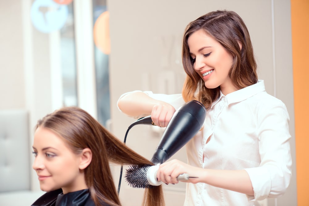 hairstylist blow drying client's hair