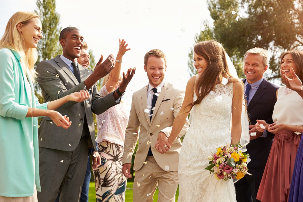wedding party bride and groom holding hands surrounded by guests