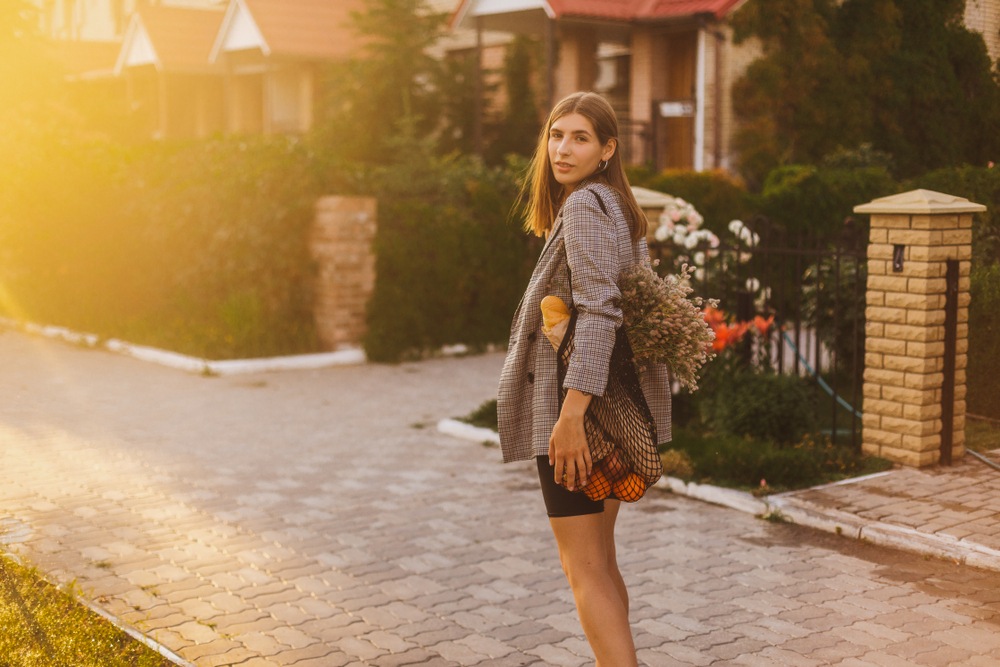 young woman at golden hour walking down a sidewalk 