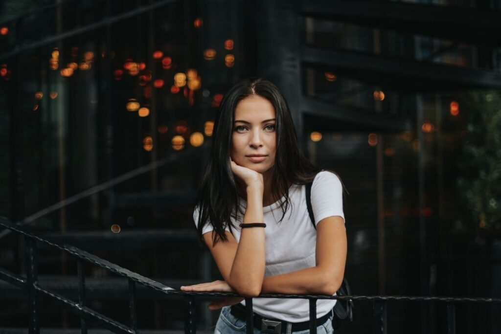 brunette woman in a white shirt leaning on a railing