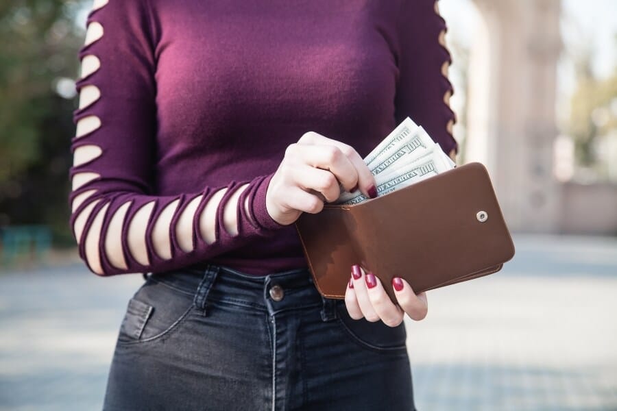 person putting money into wallet